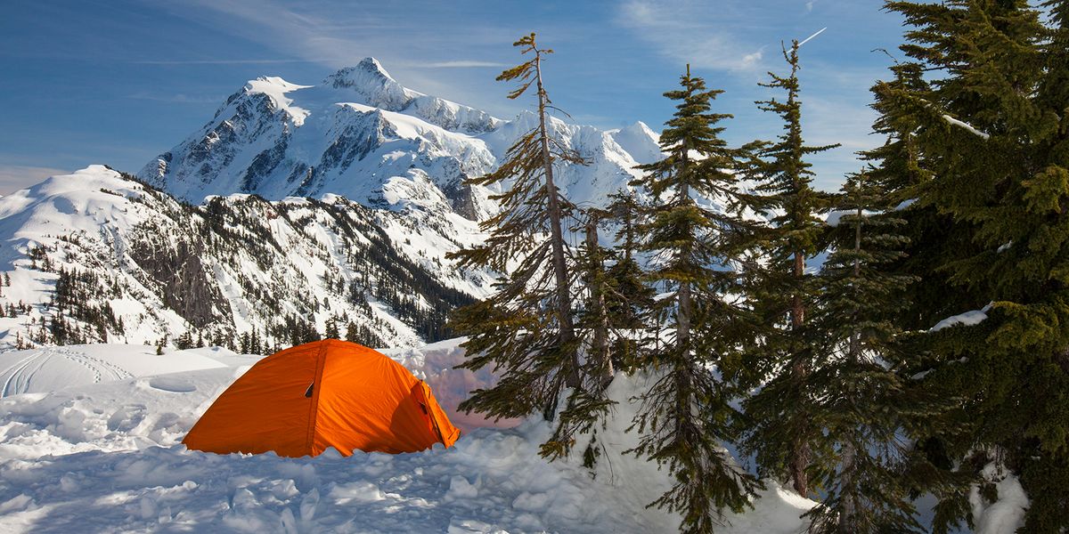 orange 4 season tent pitched in snowy mountains
