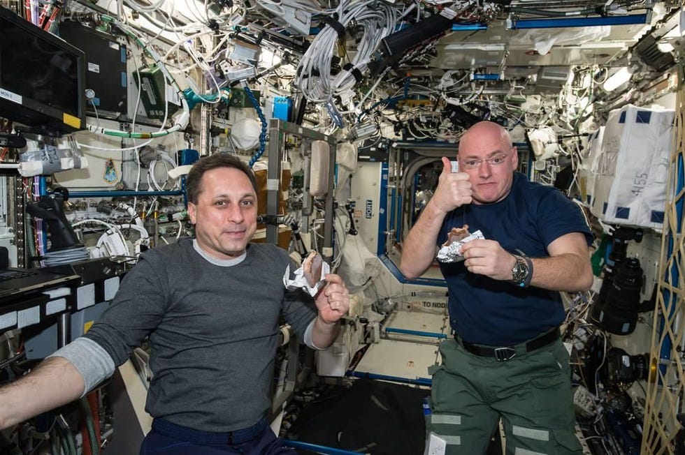 Tijdens een pauze in zijn werkrooster op het International Space Station ISS op 20 april 2015 steekt NASAastronaut Scott Kelly een duim op om aan te geven dat de kwaliteit van zijn ruimtevoedsel prima is De Russische kosmonaut Michail Kornienko ROSKOSMOS lijkt het met hem eens te zijn