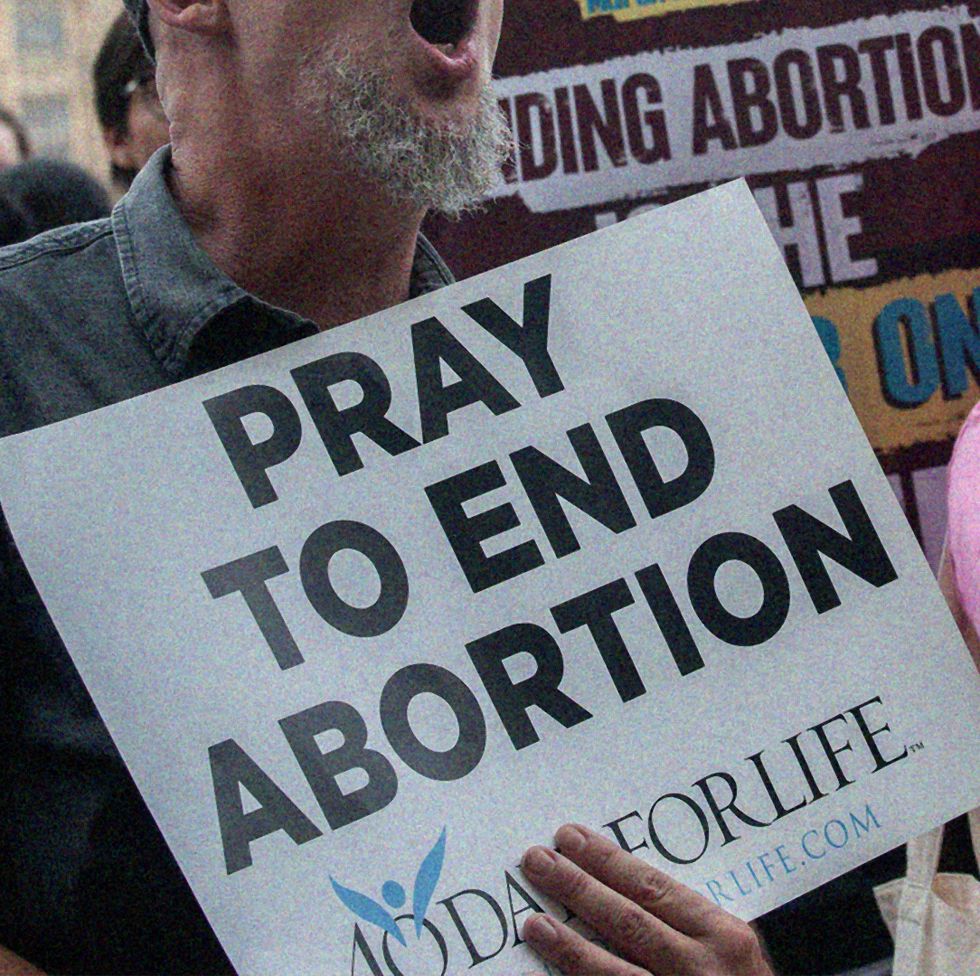 a man and woman holding a sign that protests against abortion