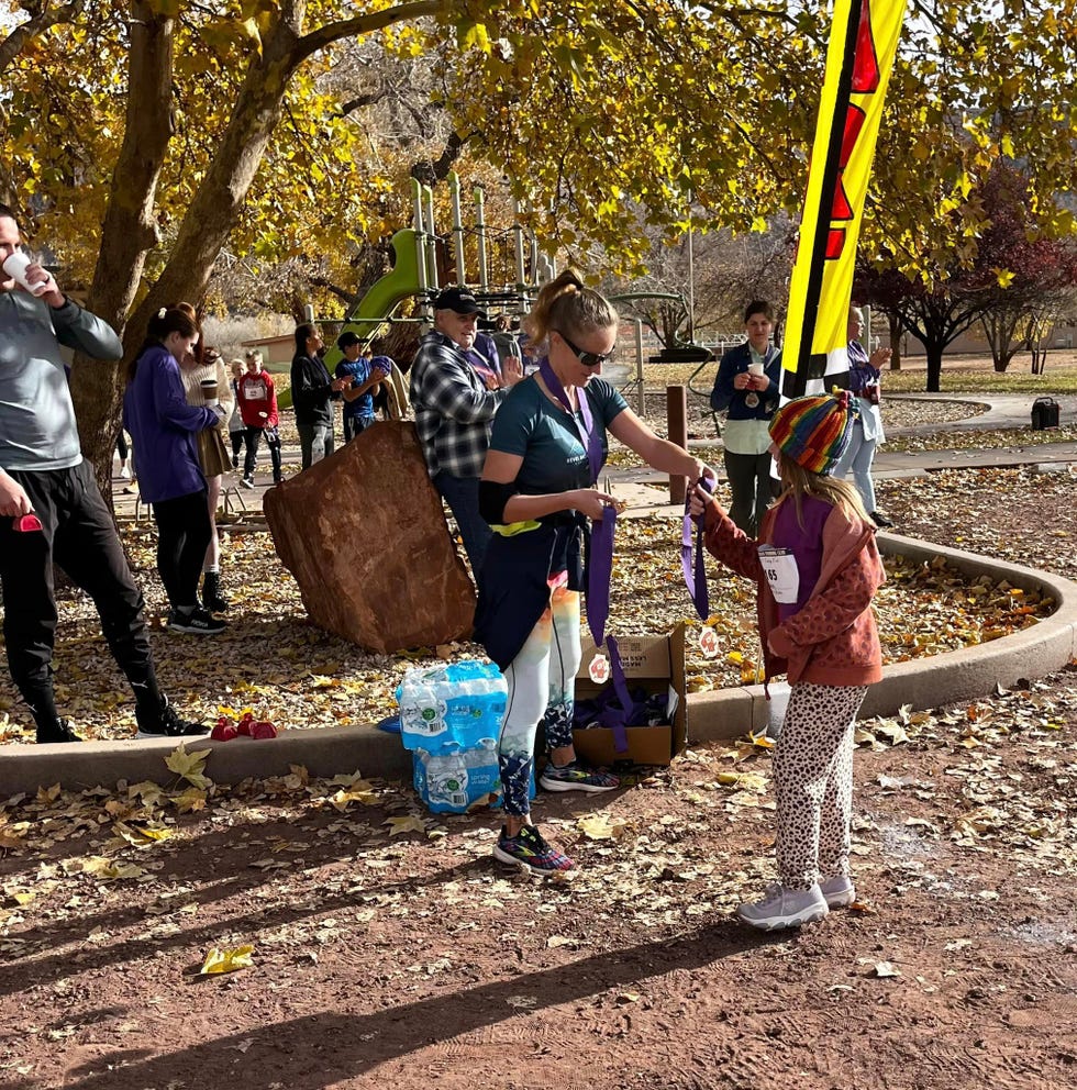 a woman hands out a medal after a running race