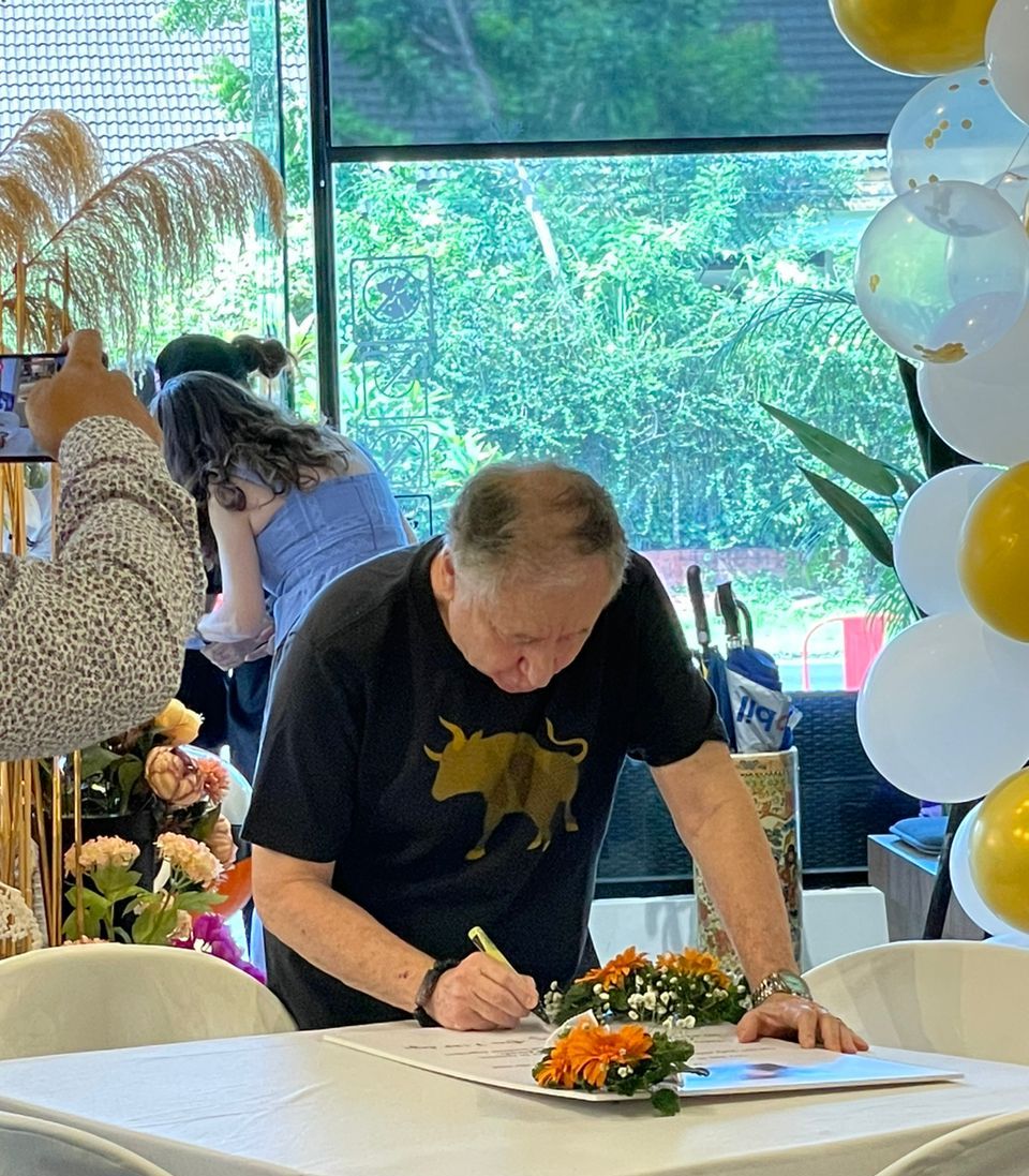 a person sitting at a table with balloons and flowers