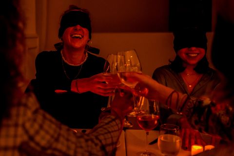 blindfolded diners toast during a dining in the dark event