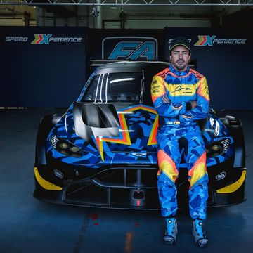 a man in a race suit standing next to a race car