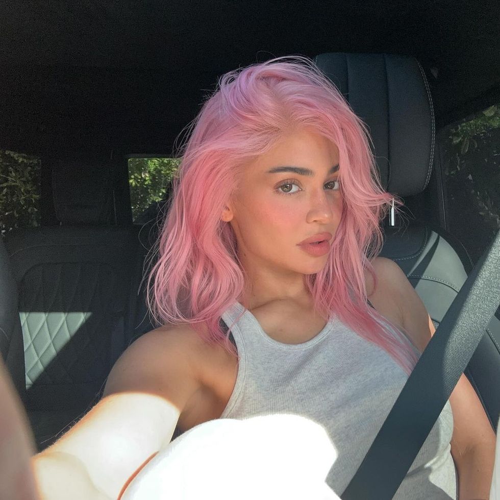 a person with pink hair sitting in a car