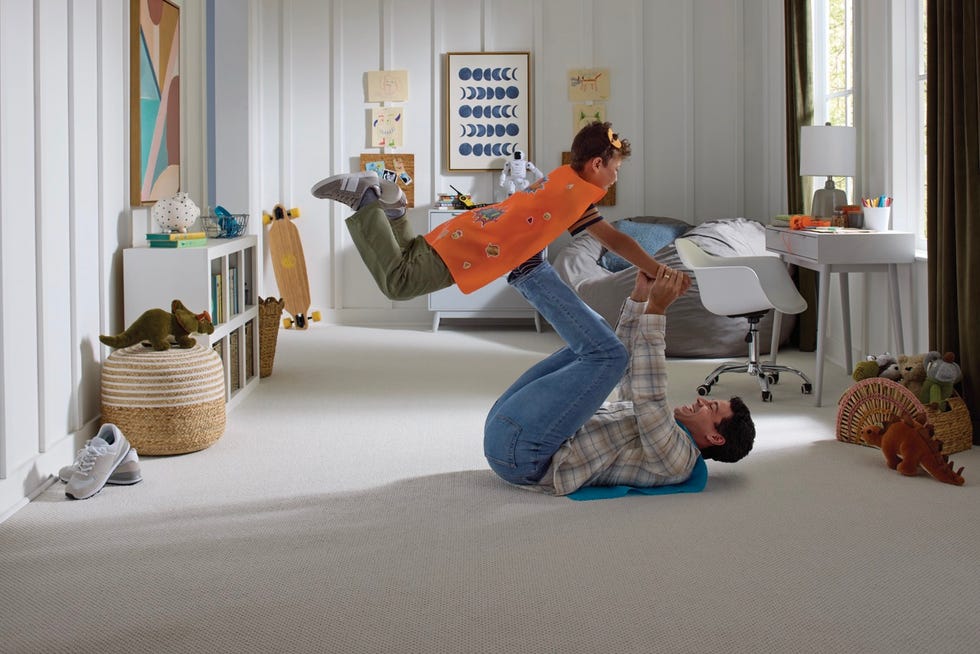 a playful indoor scene with a child being lifted in the air by an adult in a welldecorated room