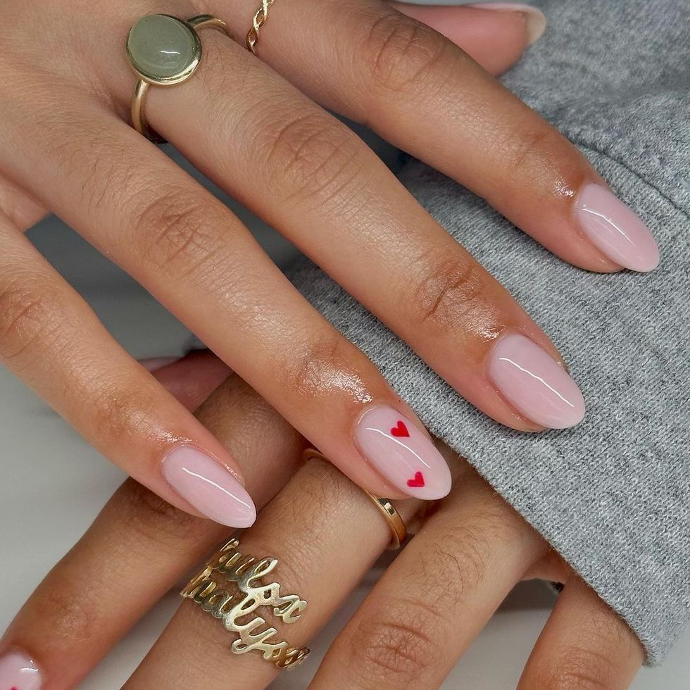 a woman's hand with pink nails and rings