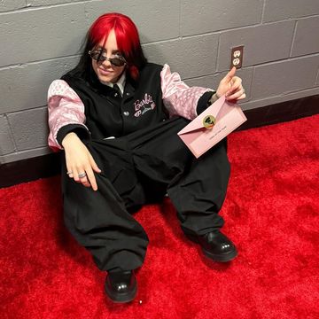 a person sitting on a red carpet holding a book and a pen