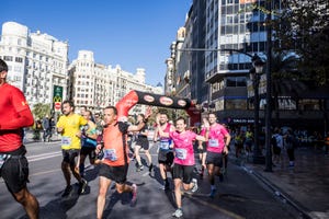 a group of people running on a street with buildings in the background