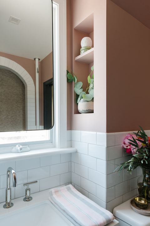 white subway tiles, pink painted walls, silver faucet, mirror, built in shelving, pink and gray hand towels