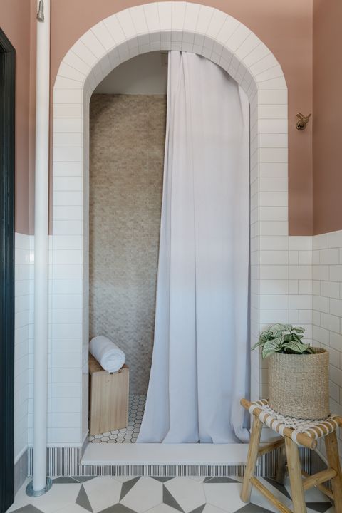 shower, pink painted wall, white subway tile, wooden stool, white shower curtain, geometric white and gray tiles