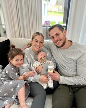 a man and woman holding a baby and sitting on a couch