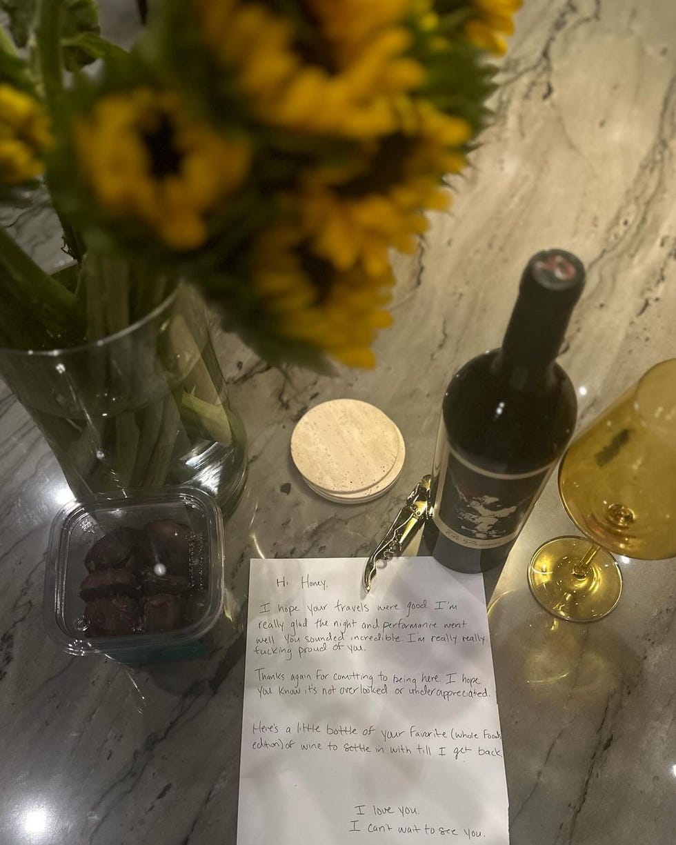 a bottle of wine next to a vase of yellow flowers