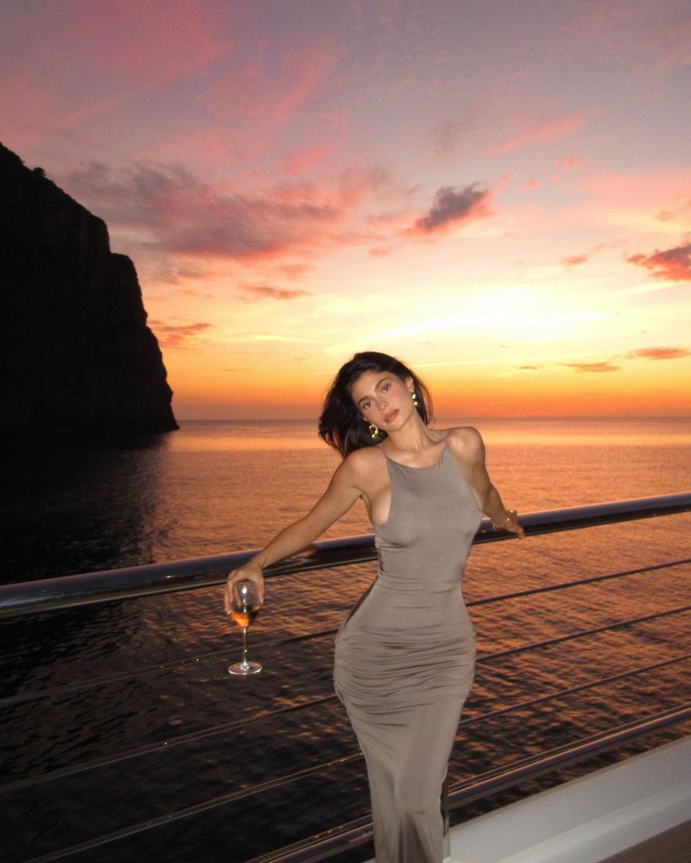 a woman holding a glass of wine on a dock by the water
