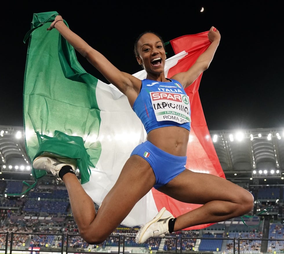 a person in a blue uniform jumping in the air with a flag in the background