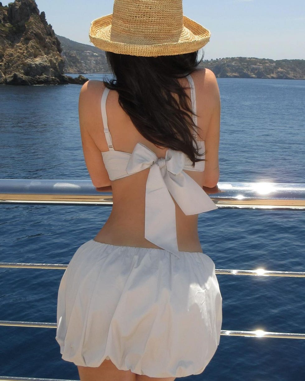 a woman wearing a hat and standing on a dock