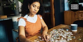 person assembling a jigsaw puzzle at a wooden table