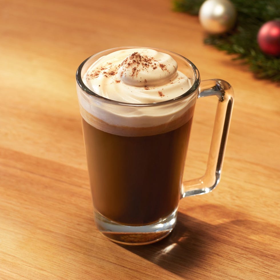 coffee topped with whipped cream and a sprinkle of cocoa in a glass cup