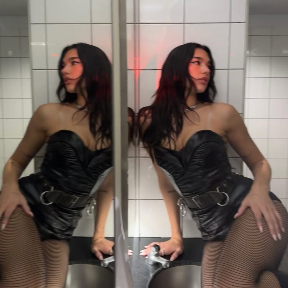 a person wearing a black outfit and fishnet stockings poses in a bathroom