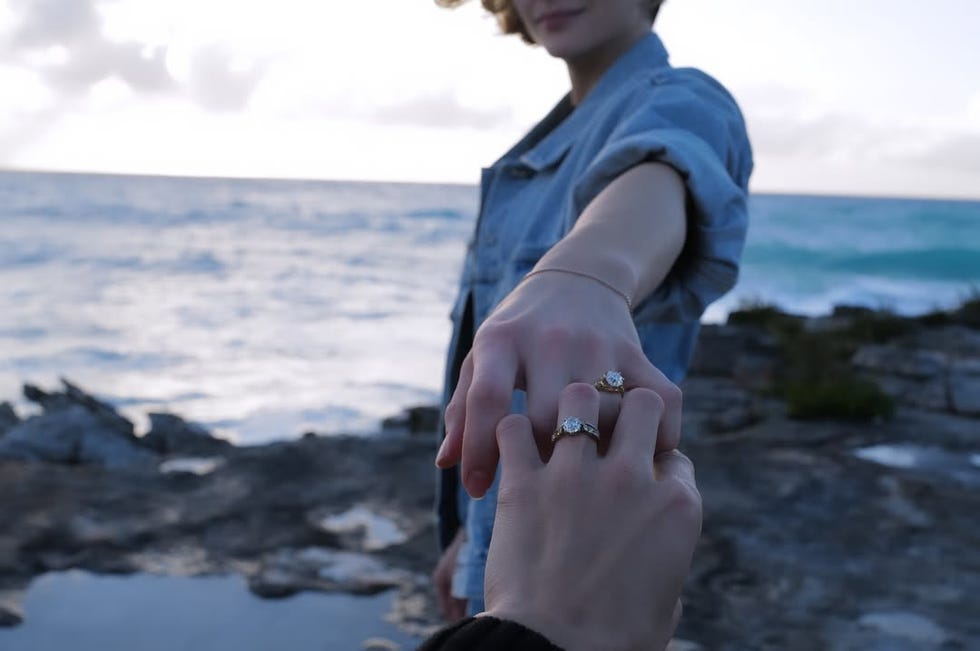 hands of two individuals holding each other presenting engagement rings