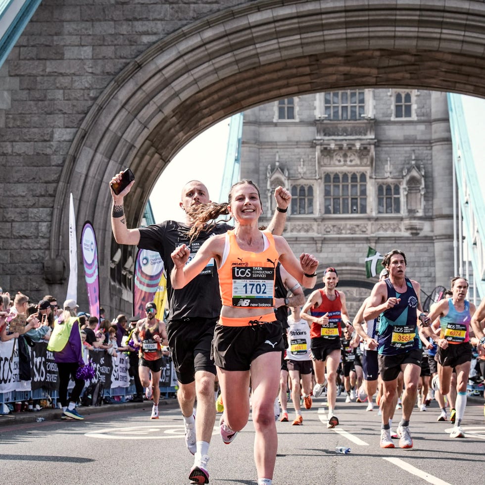 smiling runners crossing tower bridge during the london marathon
