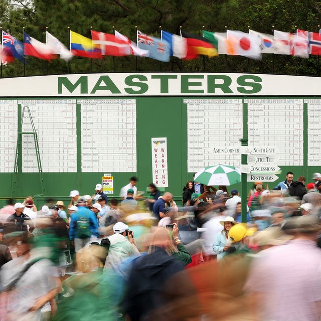 Crowd at a golf tournament under flags with a scoreboard in the background. Crowd at a golf tournament under flags with a scoreboard in the background.
