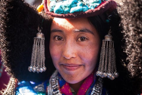 In het land van de hoge bergpas IndiaLadakh betekent letterlijk het land van de hoge bergpas Dit gebied ligt dan ook in de Himalayas in het noorden van India Op cultureel gebied hebben de inwoners van Ladakh een aantal raakvlakken met de Tibetanen  voedsel muziek en architectuur komen overeen De kleding van de Ladakhi is daarentegen iets geheel origineels De vrouw op deze foto is net getrouwd en viert dit op een groot festival dat zij samen met andere pas gehuwde vrouwen geheel uitgedost bezoeken In de feestelijke kleding  die vaak meer weegt dan het lichaamsgewicht van de jonge vrouwen zelf  voeren ze een traditionele dans op Daarna krijgen ze witte sjaals cadeau de boeddhistische manier van gelukwensen