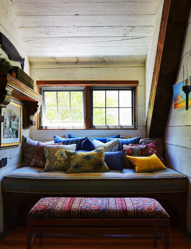 Cozy nook with a cushion-filled bench and windows.