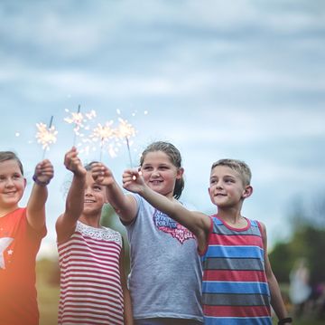 four friends holding lit sparklers in air, a time honored 4th of july activity