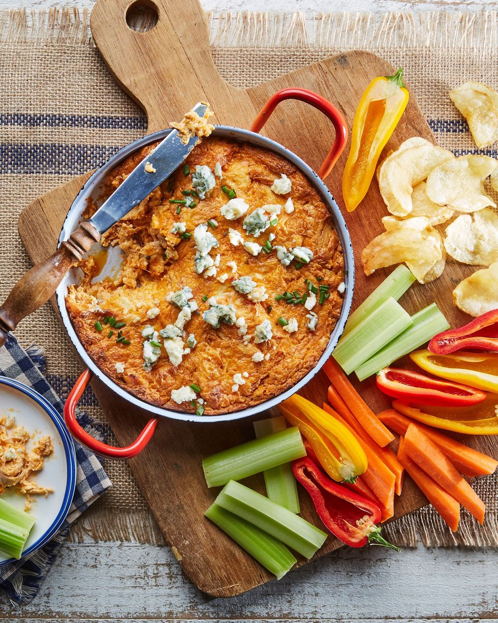 classic buffalo chicken dip in a bowl on a wooden serving board with various veggies and chips for dipping