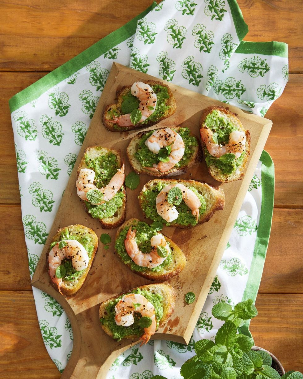 snap pea pesto and shrimp crostini arranged on a wooden serving board