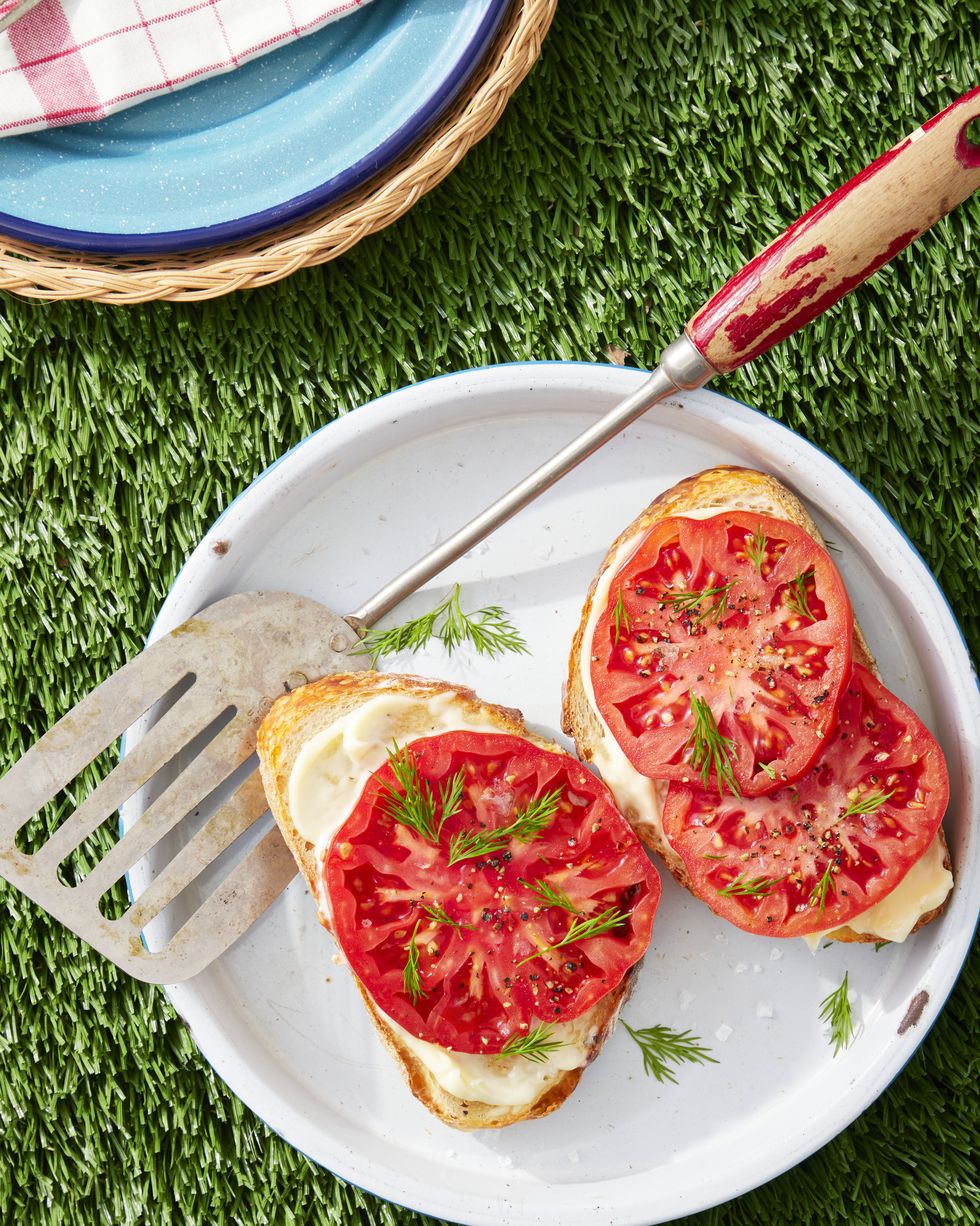 open faced tomato and dill toasts on a white plate with a spatula from serving
