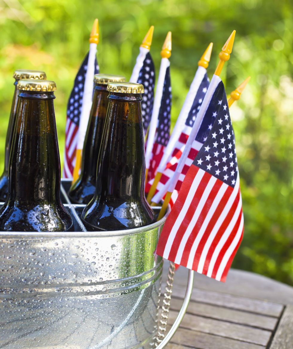 beer bottles in galvanized bucket with american flags that you might caption red, white and brew on 4th of july