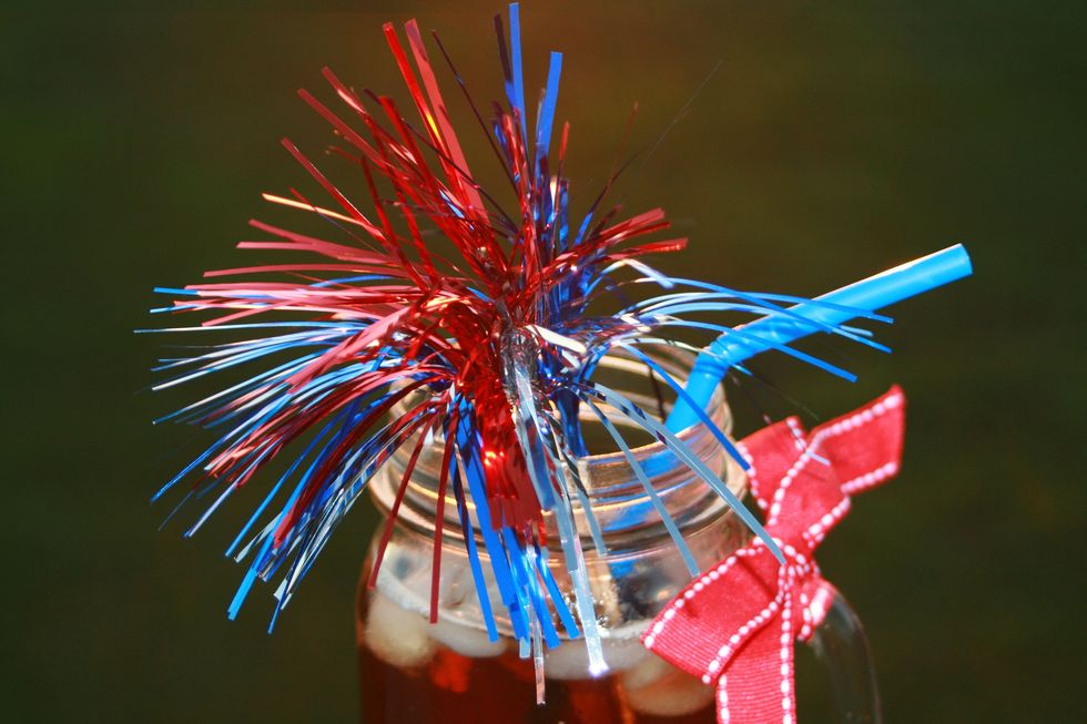 mason jar of iced tea with 4th of july decorations you might caption sippin' liber tea