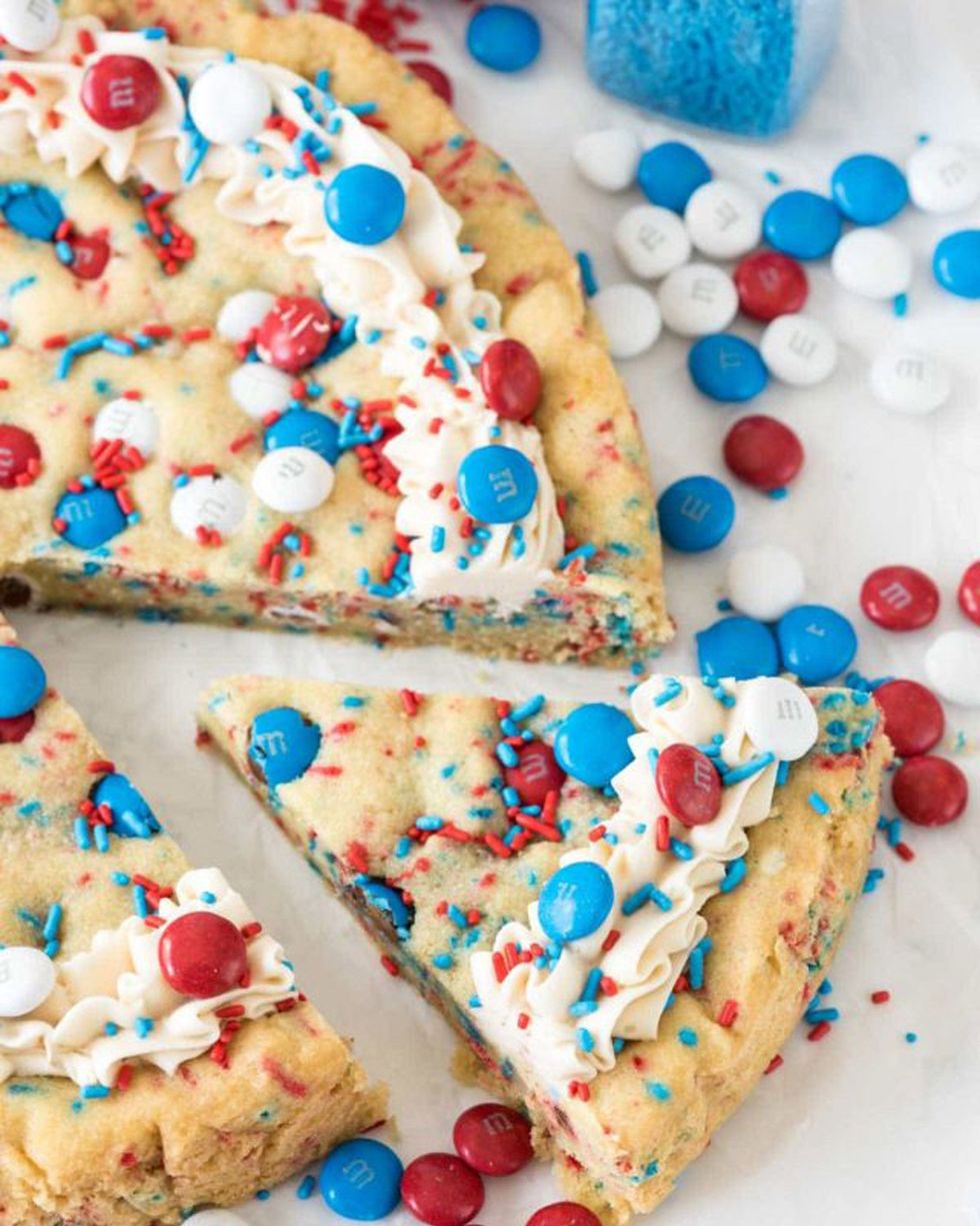 fireworks sugar cookie cake decorated with white frosting and red, white, and blue sprinkles and m and m's for 4th of july