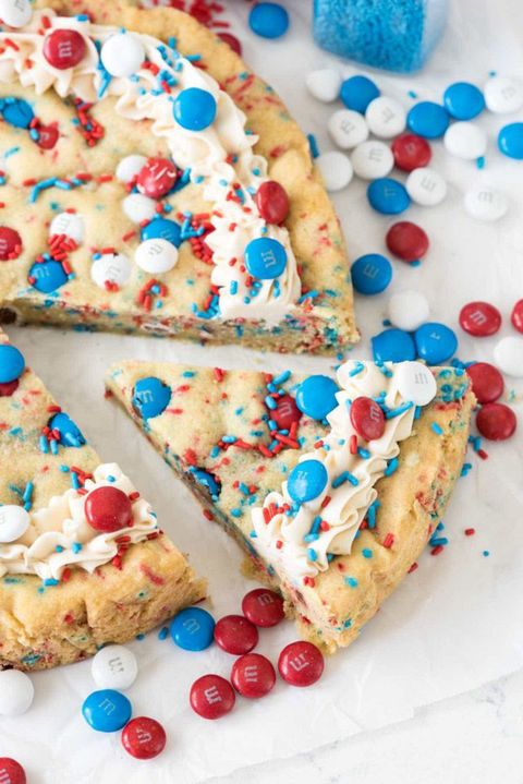 fireworks sugar cookie cake decorated with white frosting and red, white, and blue sprinkles and m and m's for 4th of july