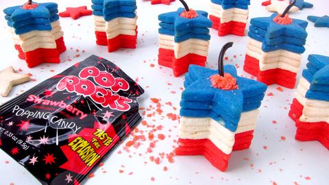 stack of red, white, and blue star shaped sugar cookies with licorice decoration on top to resemble fuse of a 4th of july firework