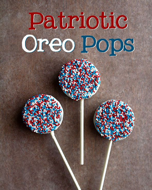 oreos coated white candy coating, covered in red, white, and blue sugar beads, and served on lollipop sticks for 4th of july