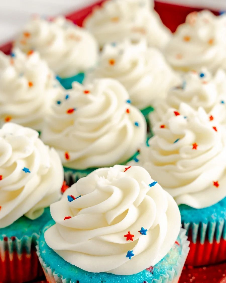 red white and blue cupcakes with white frosting and star sprinkles