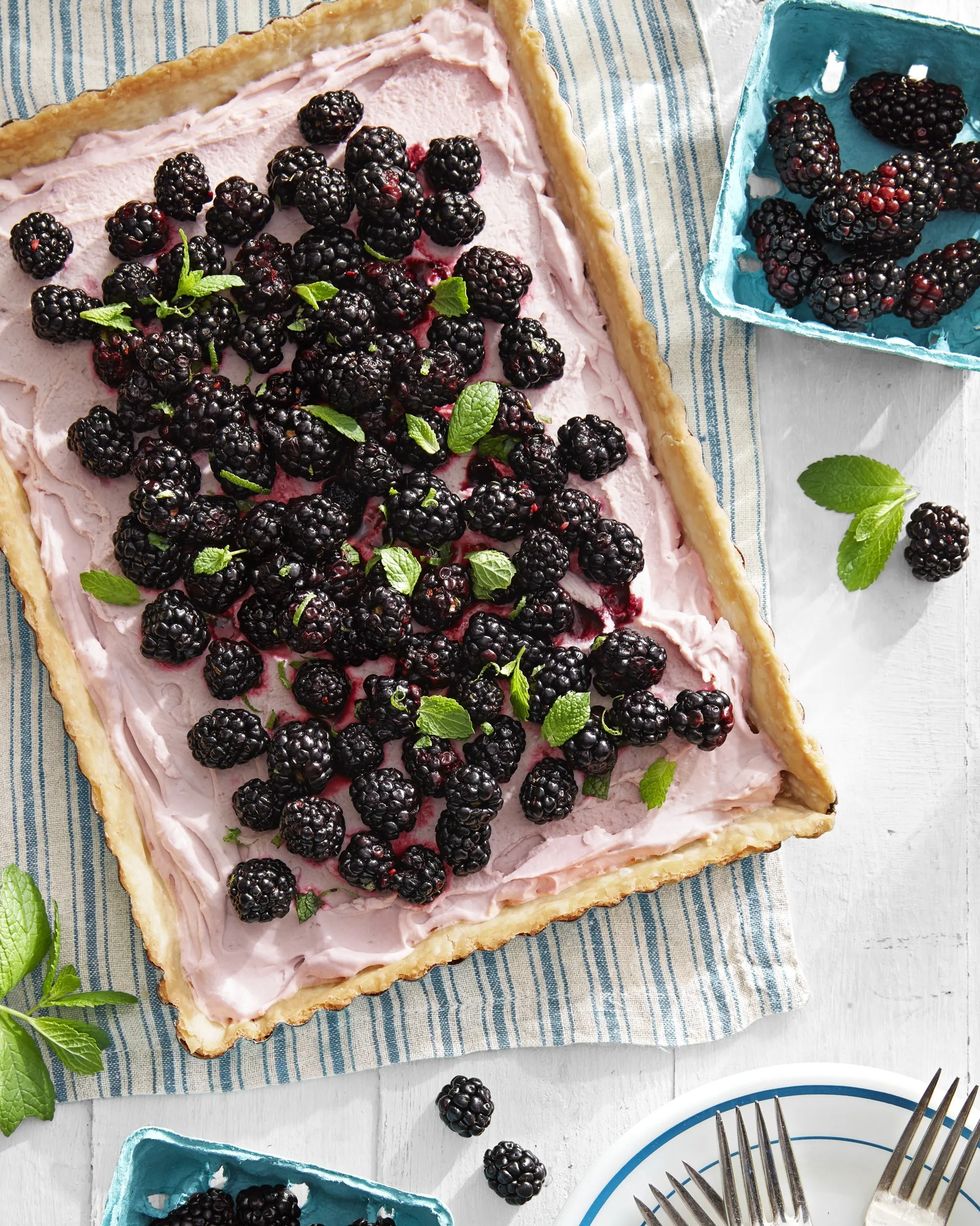 blackberry tart on a dish towel with more blackberries surrounding