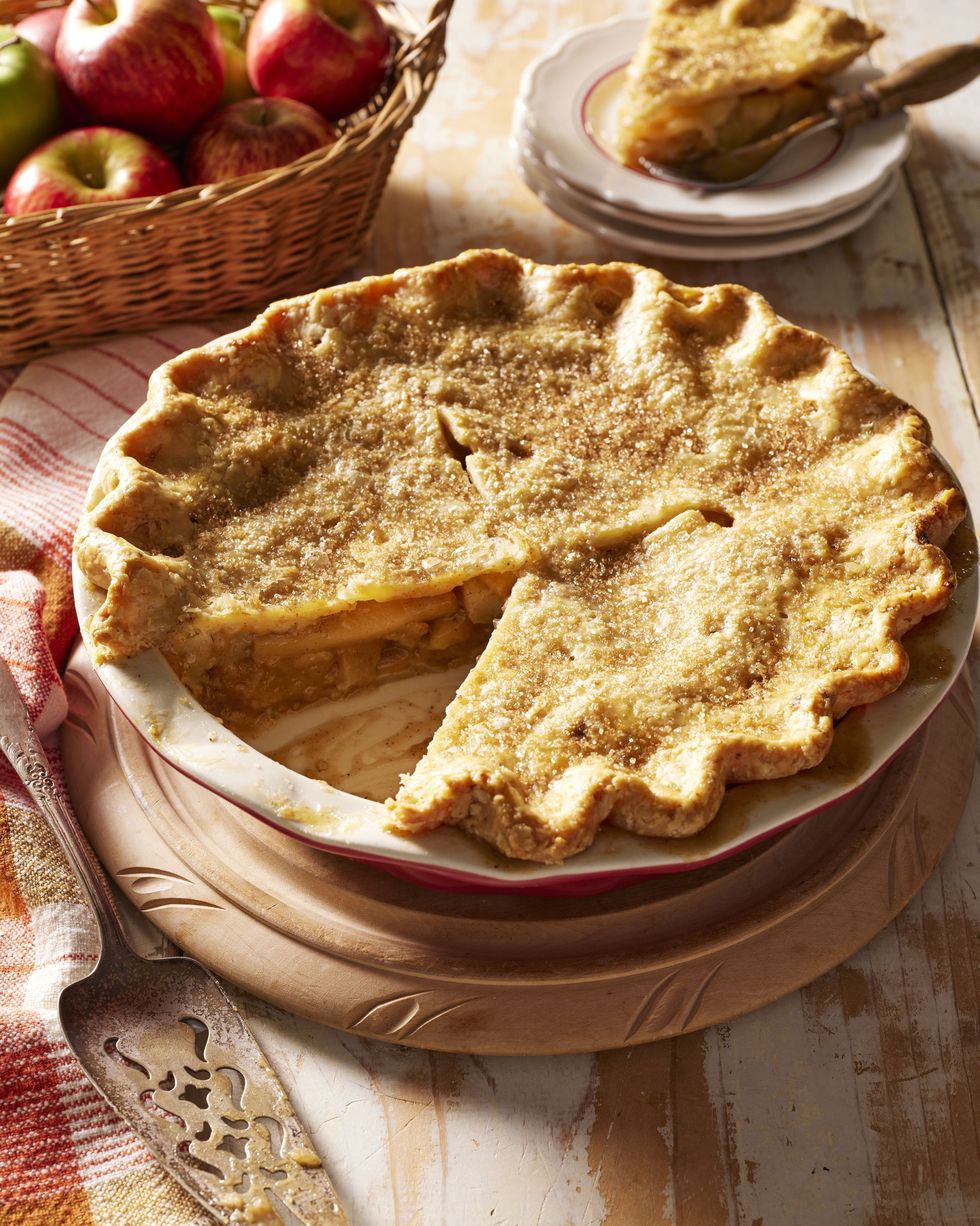 browned butter apple pie in a red pie dish with a slice removed and pie server to the side