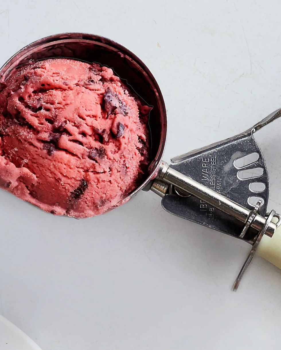 an ice cream scooper with a large scoop of homemade cherries jubilee ice cream