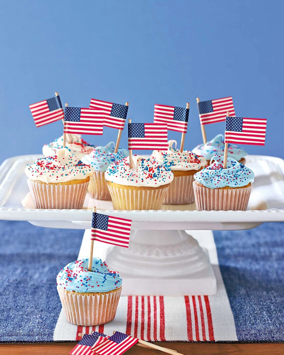 patriotic cupcakes with little american flags in them all on a raised porcelain tray