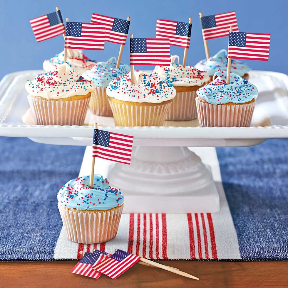 patriotic cupcakes with little american flags in them all on a raised porcelain tray on things to do on memorial day roundup
