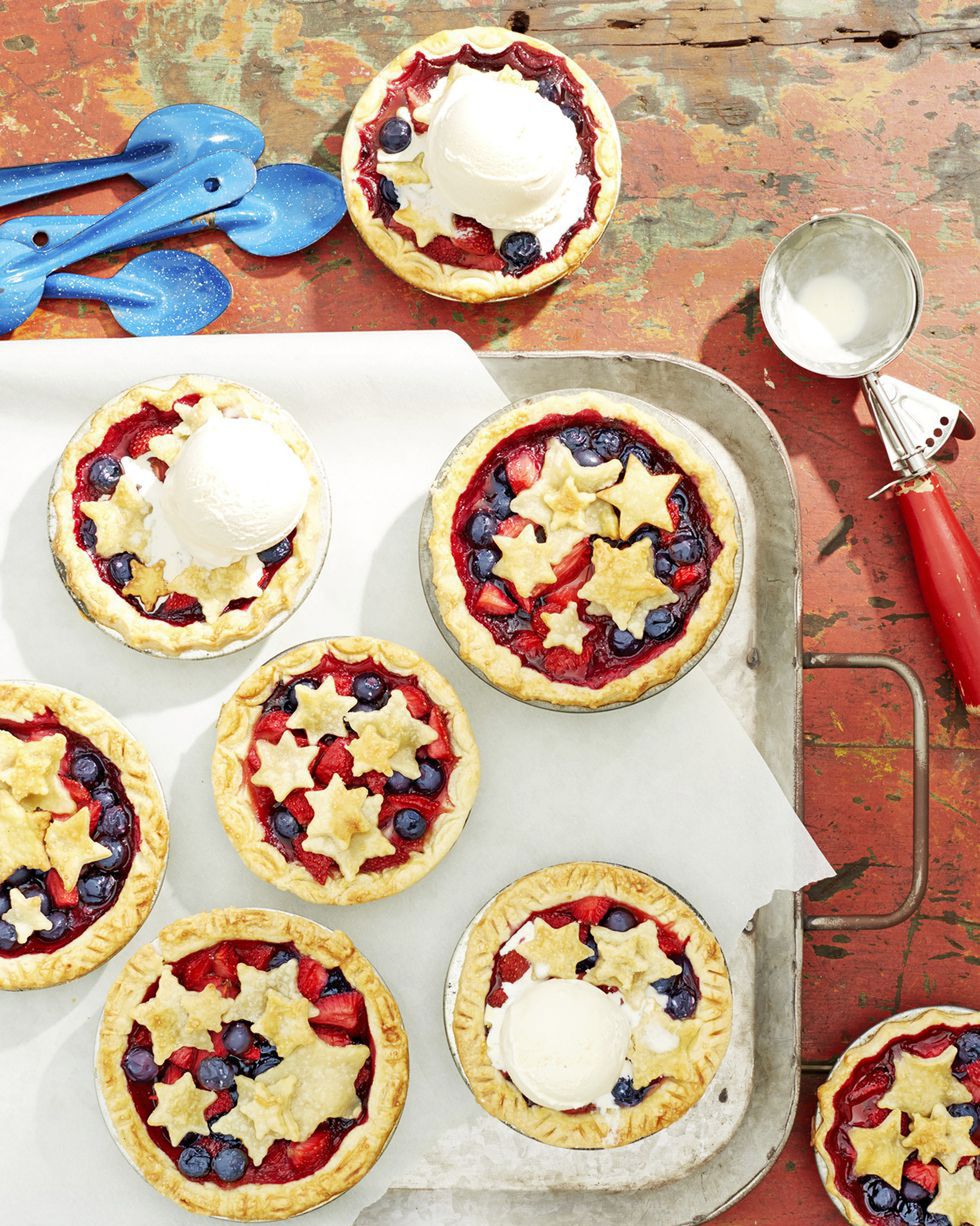 mini berry pies with pie crust stars on top and a couple topped with a scoop of vanilla ice cream