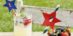 old fashioned lemonade served in mason jars garnished with blueberries, strawberries, and red, white and blue paper straws embellished with star shaped paper cutouts for fourth of july