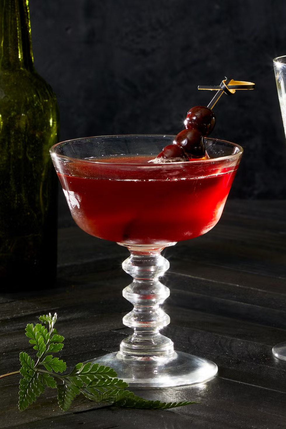 red cassis manhattan cocktail with a skewer of cherries
