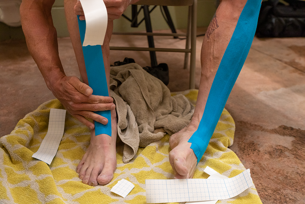 man applying tape to his legs