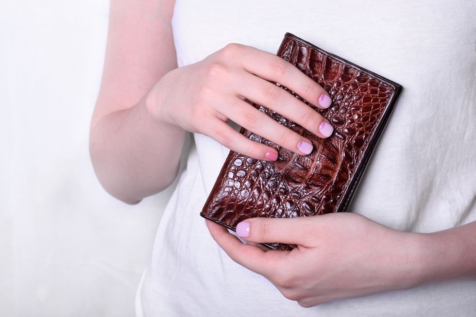 woman is holding brown leather wallet in her hands