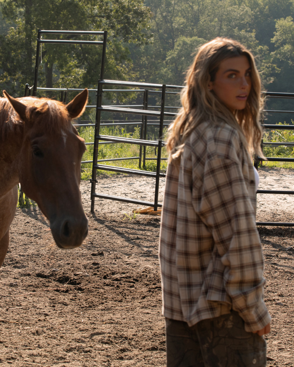 person wearing a flannel standing next to a horse