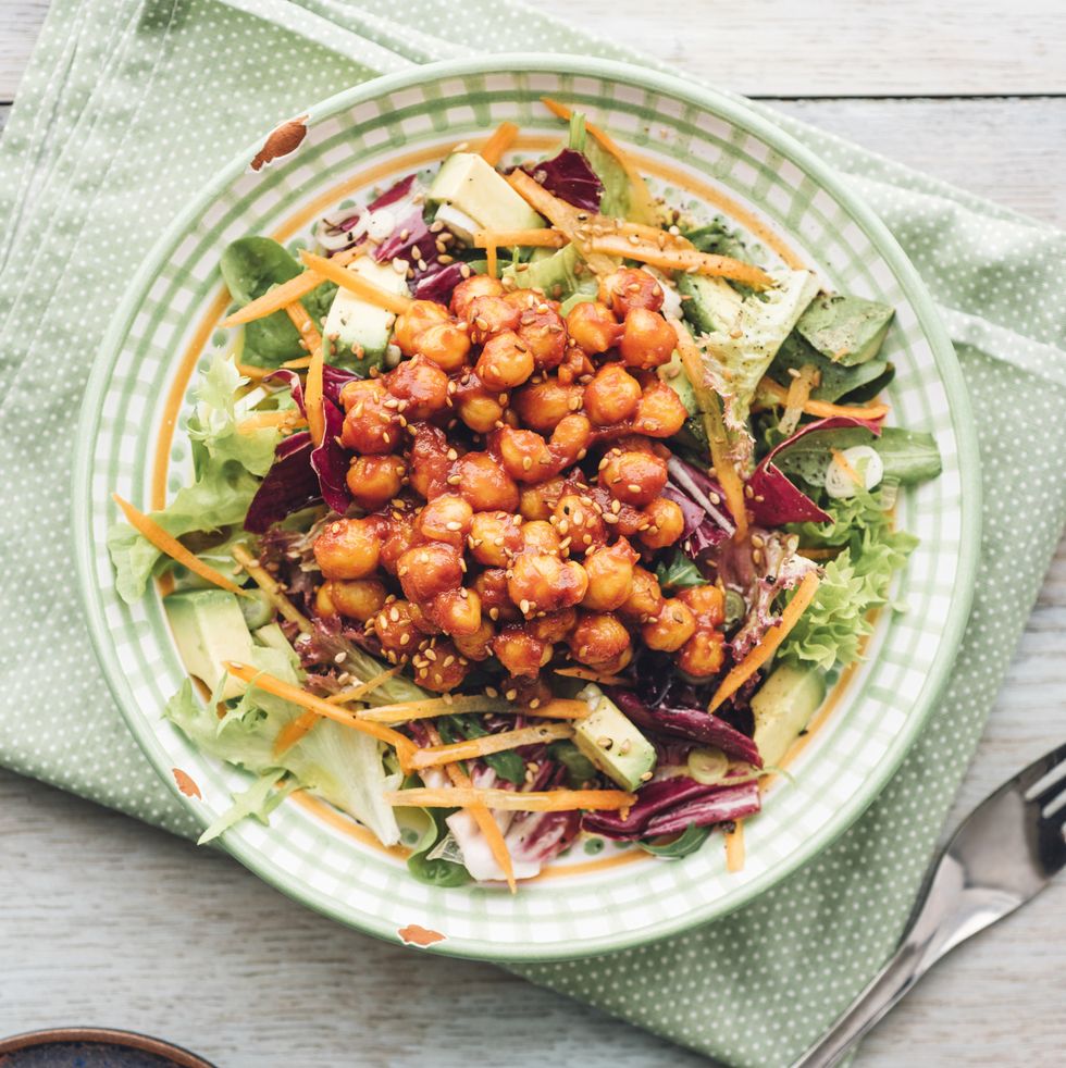 mixed raw salad with marinated, tomato, smoked paprika, honey, soy sauce, chickpeas on plate